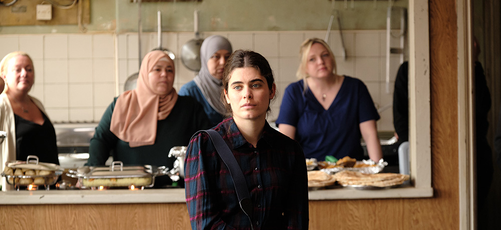Still from The Old Oak - Yari, a young Syrian woman, with others in the kitchen